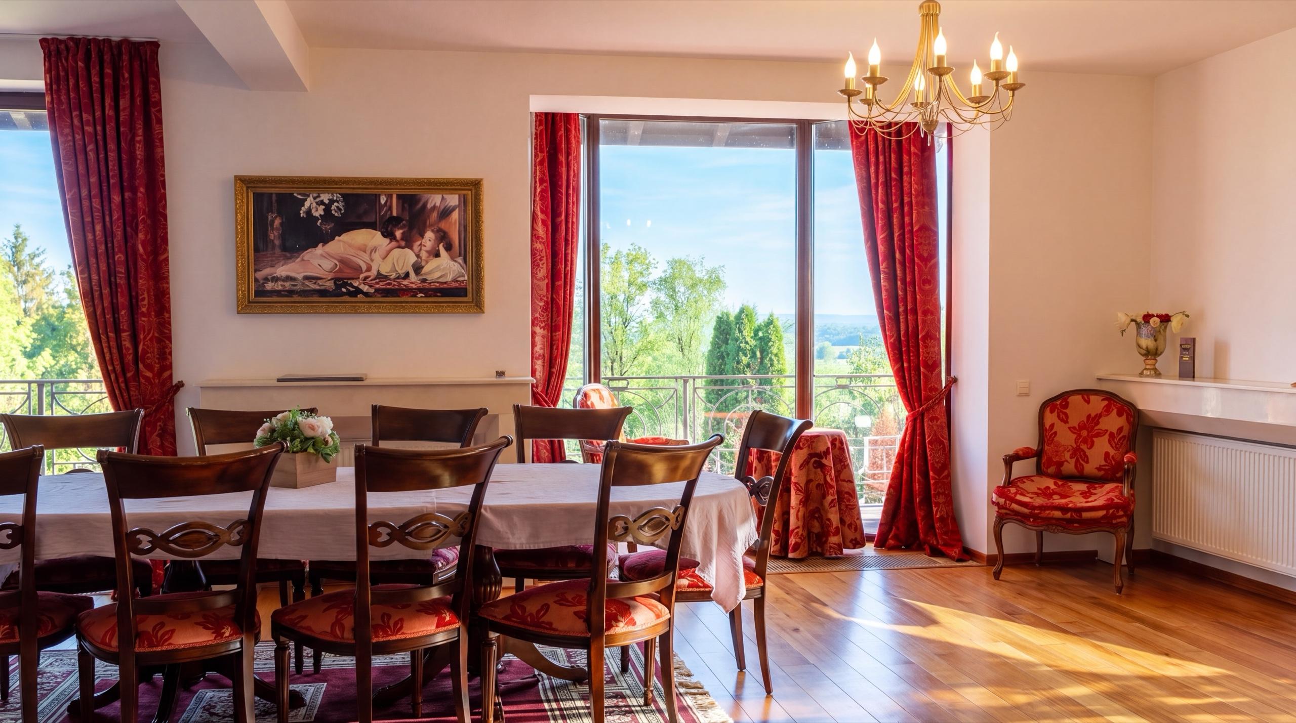 Masa lungă de sufragerie de la Hidden Hills, cu scaune tapițate în roșu, candelabru auriu și ușă-fereastră spre balcon, cu pomii și dealurile în depărtare